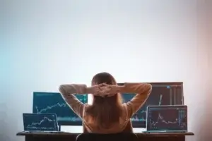 mulher olhando para a tela com gráficos do mercado financeiro